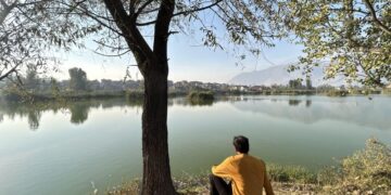 A man enjoys a quiet moment fishing at the serene Chatlam Wetland in Pampore, South Kashmir, a haven for migratory birds and nature lovers alike.