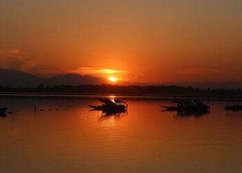 Sunset paints the waters of Dal Lake in golden hues as shikaras rest along the calm waters in Srinagar on Friday.