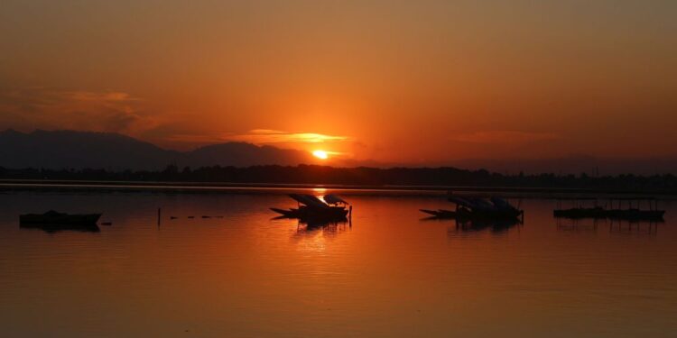 Sunset paints the waters of Dal Lake in golden hues as shikaras rest along the calm waters in Srinagar on Friday.